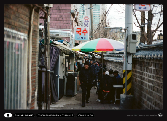 동묘의 좁은 골목길, 식당엔 젊은 사람들이 테이블에 앉아 있고, 어르신들이 멀리서부터 걸어오고 있다.