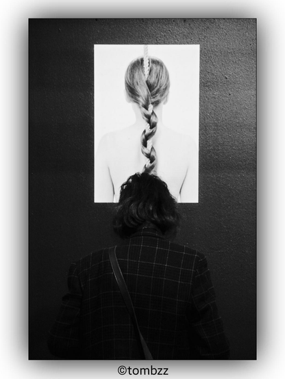 A photograph taken at an art exhibition in an art academy dormitory. The image shows an art piece on the wall depicting a scene. In front of the art piece stands a woman, creating a visual contrast. The photograph captures the interplay between the observer and the artwork, highlighting contrasts on multiple levels.