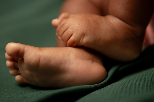 Close up detail of the feet and sole foot of a beautiful black baby girl on dark green background