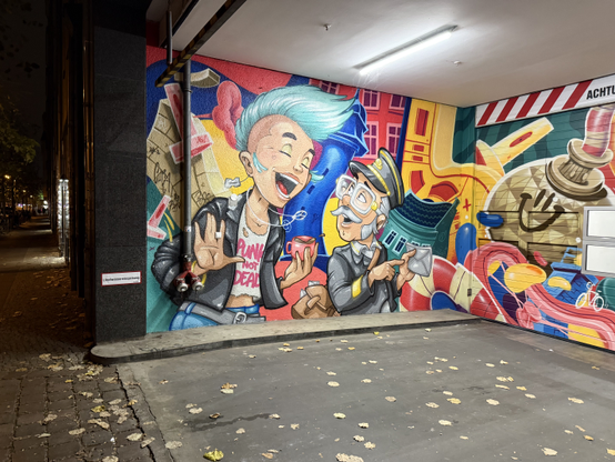 Street art of a young woman with a blue mohawk, razorblade earrings, a leather jacket, and a crop top that says "Punk is not dead" and an elderly man, with glasses, a grey moustache, a grey uniform and a grey peaked cap, holding an envelope in one hand and pointing to it with the other. The woman has a big smile, and the man also is in good spirits.

Picture taken in Friedrichshain.