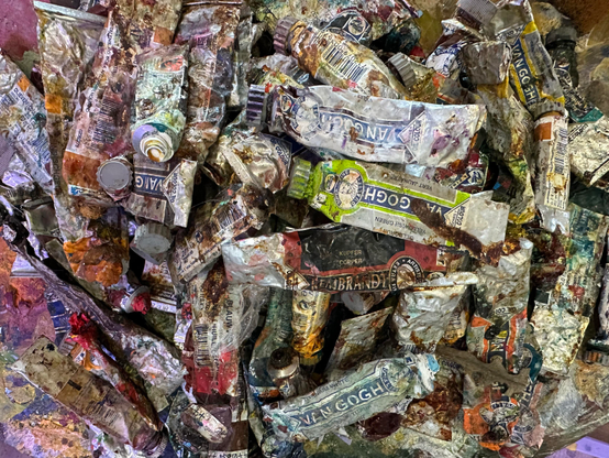 Foto superior de una montaña de botes de pinturas al óleo, muy usados y de todos los colores.