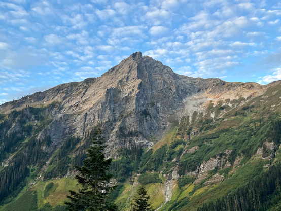 Rocky mountain with jagged ridges Light blue sky with small white clouds. 