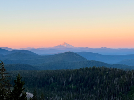 Mount Jefferson at sunrise from Mount Hood on the Timberline Trail. Beautiful orange sky above the mountain and forest.