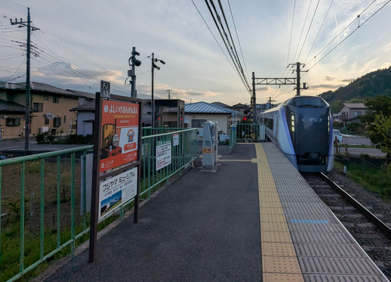Den Bahnhof von Yumeshima passiert gleich ein Nahverkehrszug.
In der linken oberen Ecke ist ein Kabelmast, dessen Drähte zum Teil den höchsten Berg Japans verdecken. 