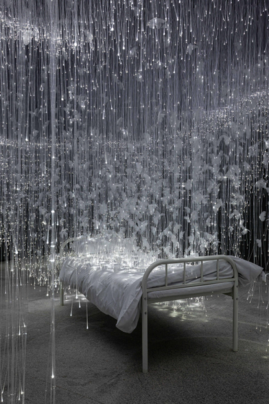 white glimmering tendrils dangle around a small twin bed
