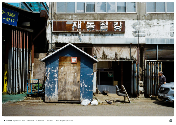 녹슬어 갈색이 되어버린 간판에 '재동철강'이란 상호가 적혀 있음. 그 아래에는 작은 집 모양의 푸른색 창고가 있음.