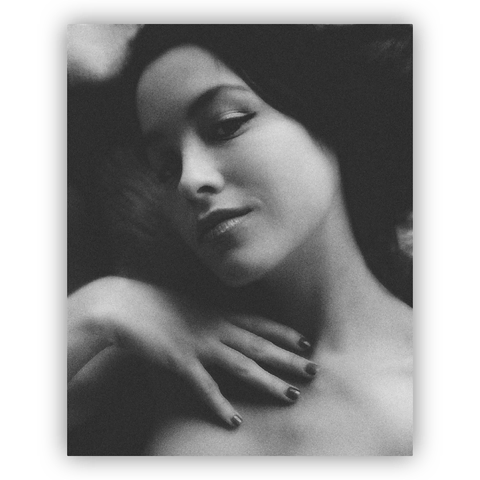 A portrait of a young woman with long, flowing hair. She is looking directly at the camera with a gentle, thoughtful expression on her face. The background is blurred, drawing attention to her facial features and the emotions conveyed through her eyes.