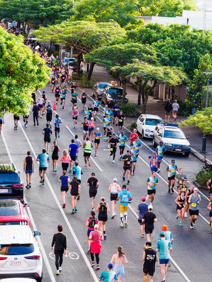 View down a street where marathon runners complete both outward and inward legs of the race, so there are crowds of runners on both sides of the road.