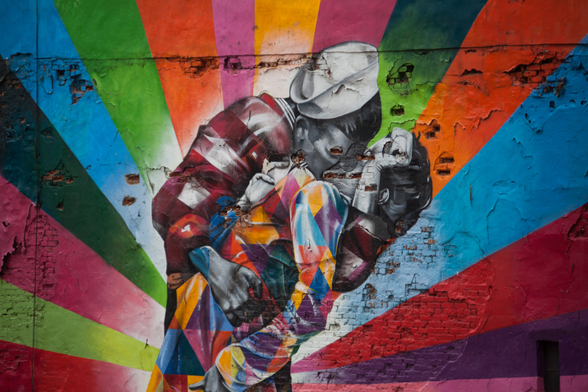 Colorful mural artwork featuring a figure in a multicolored outfit against a vibrant, rainbow-striped background.