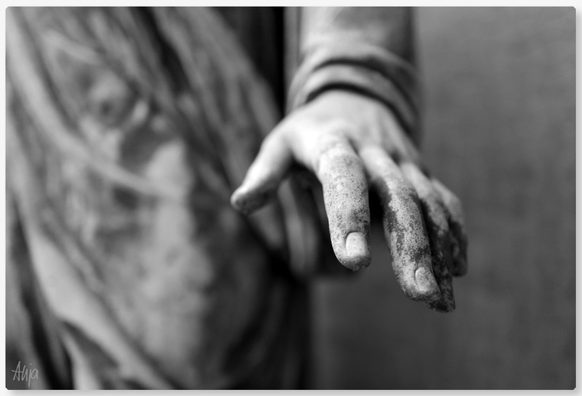 Der Fokus des schwarzweißen Bildes liegt auf der ausgestreckten Hand einer Grabfigur die nach dem Betrachter zu greifen scheint. Der Ausschnitt zeigt nur die Hand, einen Teil vom Unterarm und eine Art Gewand, das Falten schlägt im Hintergrund.

The focus of the black and white picture is on the outstretched hand of a funerary figure that appears to be reaching for the viewer. The detail shows only the hand, part of the forearm and a kind of robe that is creased in the background.