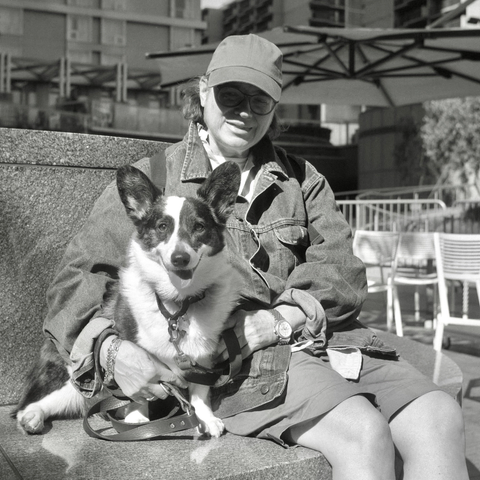 A black and white photo. Gretchen is posing with her dog Dickens in downtown Los Angeles, California. Wednesday, May 14, 2025.