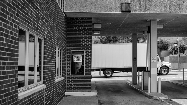 Black and white image of an urban bank with a sign reading, Sorry We’re Closed. 