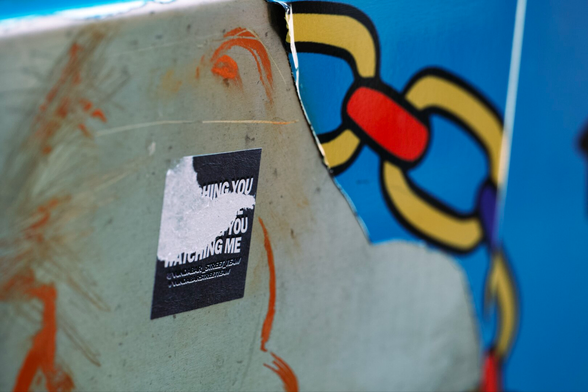 Close up shot of a utility box showing a peeling wrap, a torn sticker, and some graffiti.