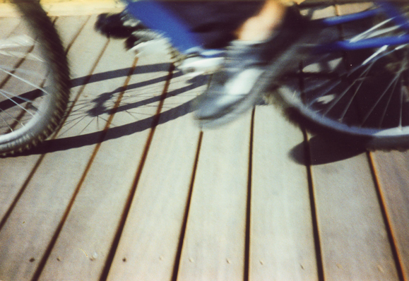 Detail of a man's foot on a bike running on wooden strips. Taken on Agfa CT Precisa analogue film using a Cosina CX2 camera.