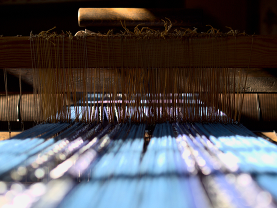 Detail of an old loom (in a museum) combining contrasts of warm and cold colors and hard and soft contours
