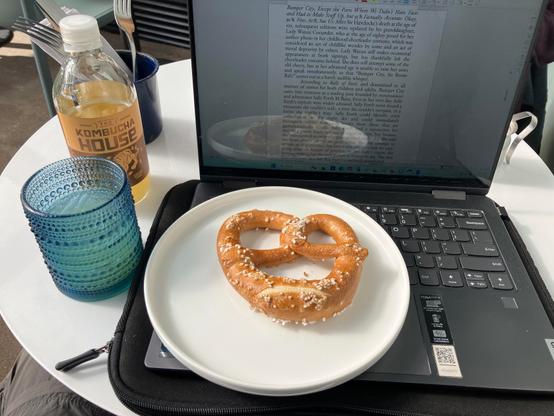 Laptop computer with a giant pretzel and a glass of kombucha