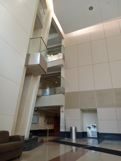 A view of an atrium from below with there levels and a small balcony that juts out from the second floor.