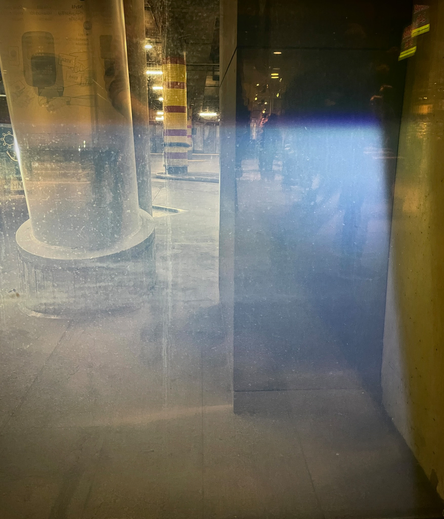 Through some light shining on a window a bus terminus can be seen, showcasing concrete pillars.