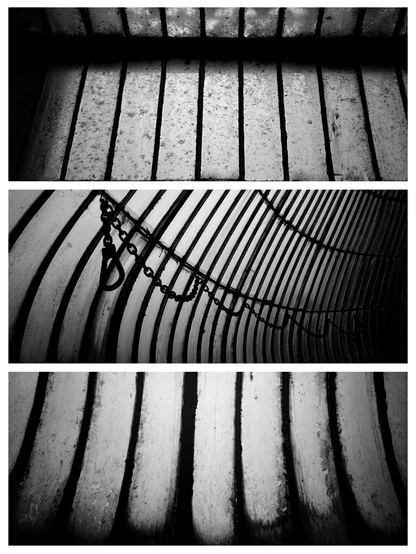 Black and white triptych of photos arranged vertically, depicting opaque and dirty panes of glass set in thin metal frames. The top and bottom photos depict panes running vertically and the middle photo shows panes curving around to the right with a metal chain and hook suspended in loops along the middle of the photo. The mood of all three photos is dark and and sombre