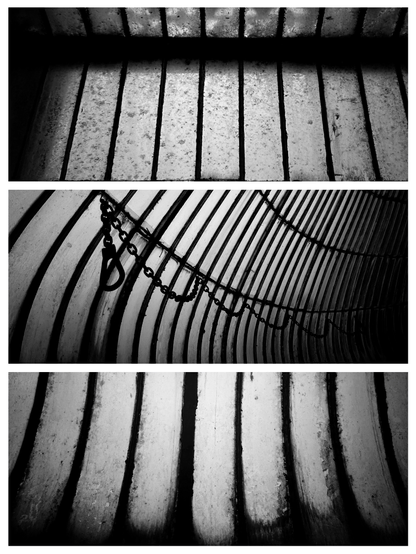 Black and white triptych of photos arranged vertically, depicting opaque and dirty panes of glass set in thin metal frames. The top and bottom photos depict panes running vertically and the middle photo shows panes curving around to the right with a metal chain and hook suspended in loops along the middle of the photo. The mood of all three photos is dark and and sombre