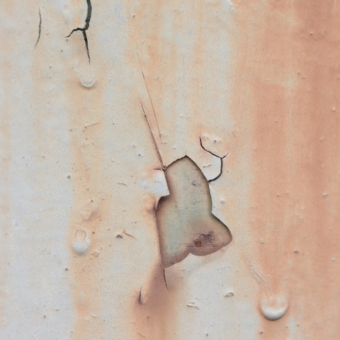 A closeup of a light pole showing broken paint and surface rust.