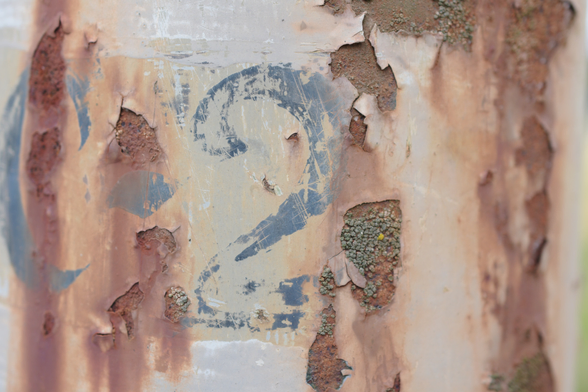 A closeup of a light pole showing lots of rust breaking through the paint and a faded numeral 2 in a blueish grey. 