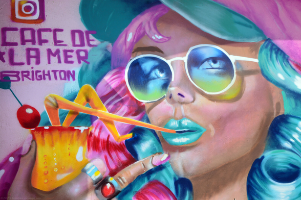 Detail of a street art mural by Sean Lyons a.k.a. Glimmertwin. On one of the Kings Road arches next to Café de la Mer. Freehand spray paints depicting a young woman holding a cocktail. Brighton seafront, Sussex, UK.