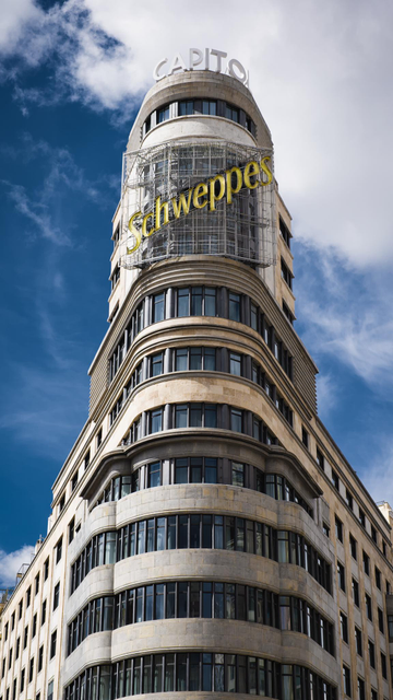 Foto de un edificio icónico de la plaza de callao de Madrid en el q se lee CAPITOL en el atico y bajo este un cartel publicitario luminoso apagado de Schweppes.