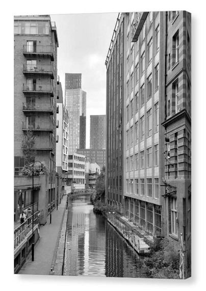 Black and white portrait photograph showing tall buildings either side of a canal.  The image is shown printed upon a box canvas.