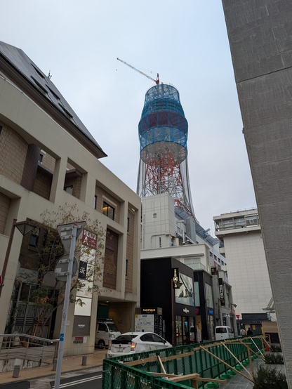 電波塔を警固参道から見たところ。全体に網が掛かって上にクレーンが載っている。2025年2月。