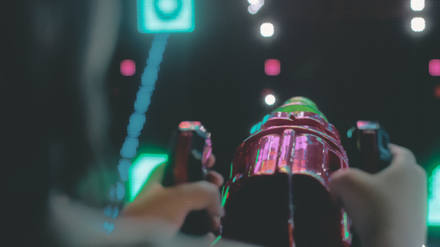 A closeup of someone’s hands on an arcade space gun