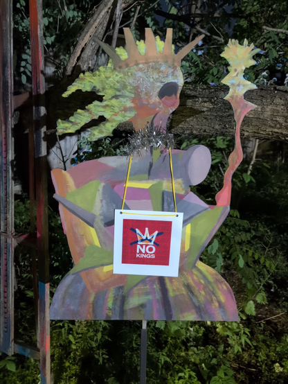 No Kings sign hanging from an abstract, outdoor art installation.