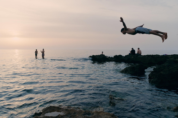 A guy captured in the air while cliff jumping