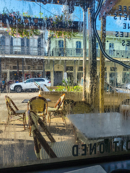 Outdoor tables and chairs and a truck bed full of plants for sale through a window with condensation. 