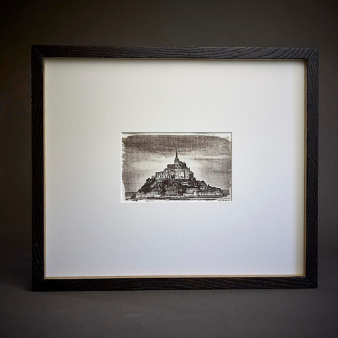Black and white argyrotype print of Mont Saint-Michel monastery. Visible brushstrokes in the emulsion create an aged, photographic effect. The artwork is presented with a wide mat (passe-partout) and a slim, front-tanned oak frame.