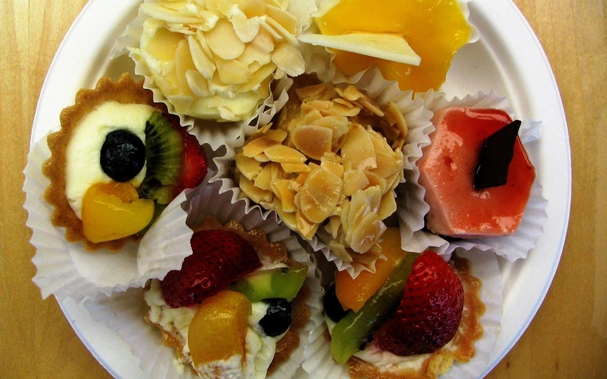 Overhead view of a plate of assorted small pastries, many involving glaceed fruit.