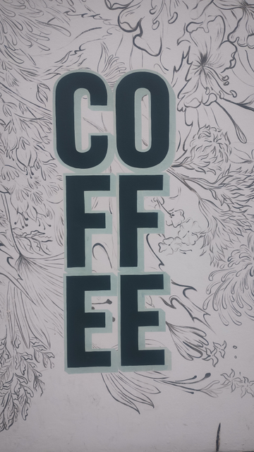 Sign on cafe wall spelling out "coffee", but two letters at a time, vertically, so "co", then below "ff", then "ee"