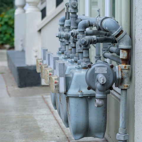 A closeup on a line of utility meters in front of a building