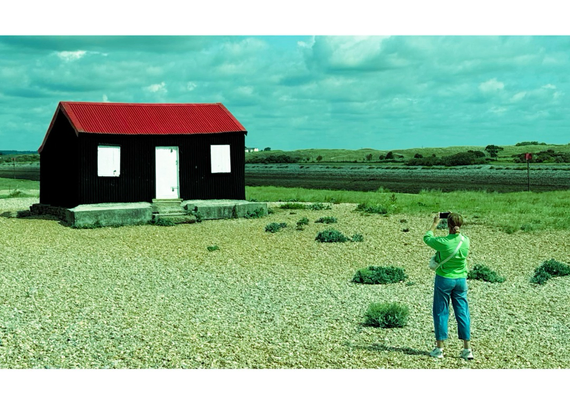 someone taking a photo of a hut with a red roof 