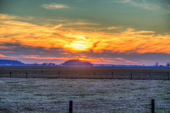 Lost HIll Under a Dazzling Sky

A brilliant sunset sets the sky ablaze with vibrant hues of orange and yellow, casting a warm glow over a vast, open field.