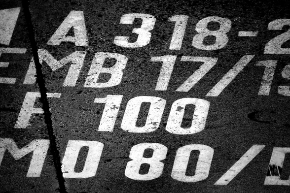 Letters and numbers are painted on the asphalt at the gate of an airport.