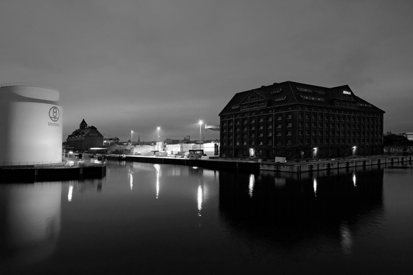 A night scene at an inland port with buildings and a gas tank.
