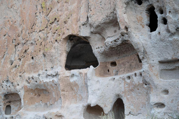 Interior view of a cavate carved into the soft volcanic rock at Bandelier National Monument, showing recessed rooms, niches, and naturally weathered surfaces used by Ancestral Puebloans for shelter.