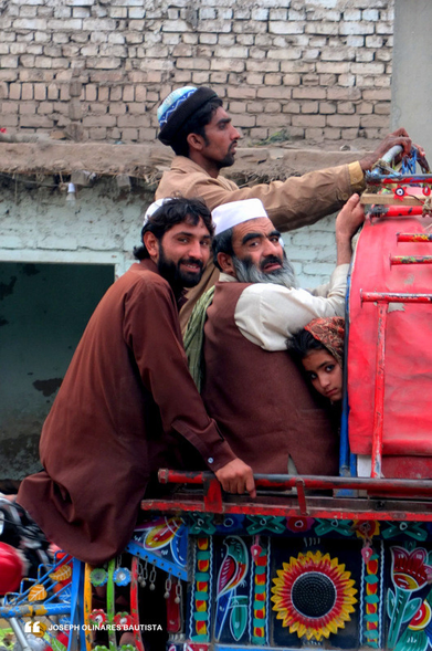A photo of what appears to be a family (with a little girl) in a colorful moving public vehicle in Peshawar, Pakistan. Photo taken in 2013 by Joseph Bautista.