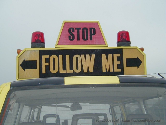 A closeup of the tail of a Follow-me-Car on an airport field, showing the "follow me sign".