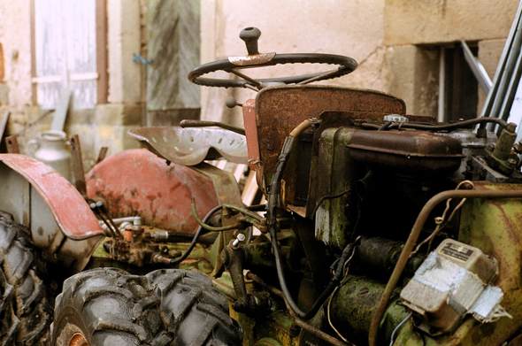 Colored photography of a tractor with open motor. The picture is taken close up.