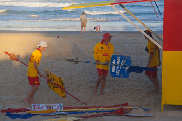 Surf lifesavers on a beach handling beech warning signs.