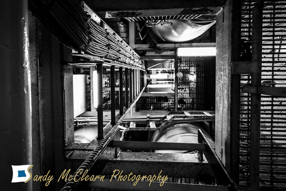 Looking up a vertical telecoms raceway with multiple cables, pipes, and trays.