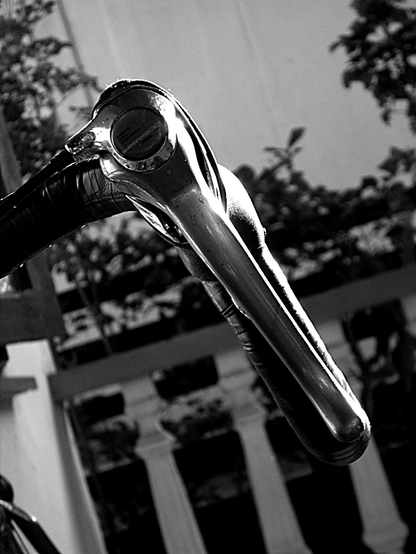  The photograph shot in monochrome is focused on a bicycle handlebar. The handlebar is prominently featured in the foreground, with a shiny, metallic finish that reflects light, highlighting its contours and the grip area. The handlebar is attached to a black rubber grip, which is partially visible. The background is in smooth bokeh, showing a building with white columns and potted plants, suggesting an urban setting. The lighting creates a dramatic contrast, emphasizing the texture and form of the handlebar.

 Ovis2-8B

🌱 Energy used: 0.148 Wh