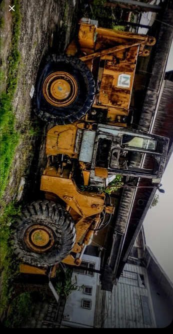  The photograph composed on an Android, shows a large, yellow construction vehicle, likely a front loader or a similar type of heavy machinery, parked on a dirt surface. The vehicle is old and shows significant signs of wear and rust, with its paint chipped and faded in places. The tires are large and rugged, suitable for heavy-duty work, and the vehicle's cabin is partially visible, with the windows and door frame showing signs of age and neglect. The background includes a building with a dark roof and a white wall, suggesting an industrial or rural setting. The sky is overcast, and there is some greenery visible around the vehicle, indicating it is not in a completely barren area. The vehicle is positioned at an angle, with the front facing the right side of the image, and the cabin is on the left side.

 Ovis2-8B

🌱 Energy used: 0.203 Wh